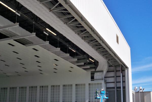 Exterior of Gulfstream Paint Hangar. Large white building and blue sky.